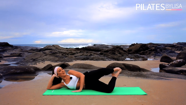 Lisa demonstrates a Pilates exercise on a yoga mat, wearing sportswear.