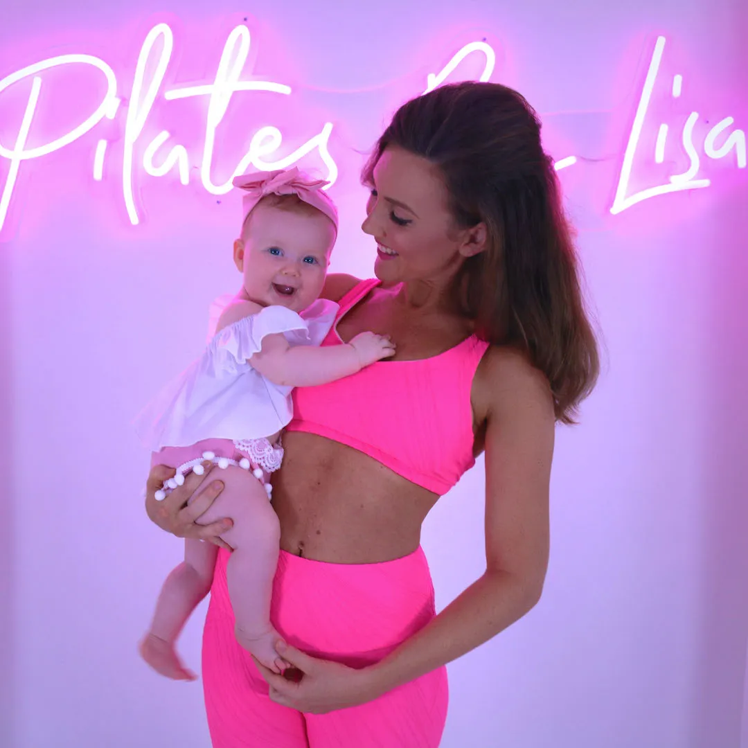 Lisa demonstrating a Pilates exercise, wearing activewear in a vibrant setting.